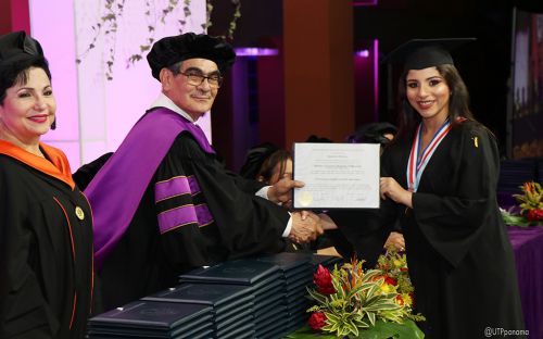 Graduanda recibe diploma de manos del Rector.