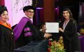 Graduanda recibe diploma de manos del Rector.