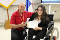 Mgtr. Juan Del Cid entregando el pin a una estudiante del capítulo de honor