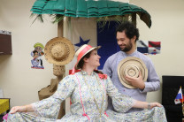 Compartiendo sonrisas y cultura Dos estudiantes de intercambio con trajes típicos panameños posan bajo un pequeño techo de paja con la bandera de Panamá de fondo.