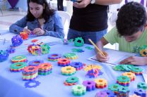 Niños participantes jugando con piezas de colores en una mesa.