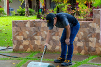 Persona usando hidrolavadora para limpiar una malla en el área verde del Centro Regional.