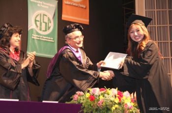 La estudiante de mayor índice, recibe su diploma de manos del Vicerrector.