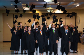 Estudiantes lanzan sus birretes como celebración.