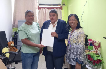 Profesora Eira Cumbrera recibe de Licda. Itzel Ortega, contenidos de su carrera en un formato braille.